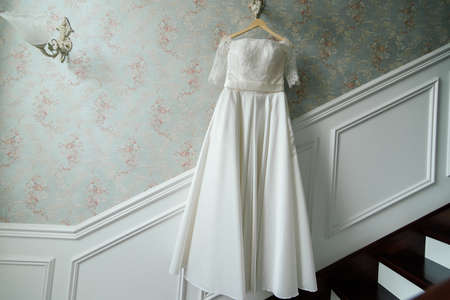 Bride dress hangin on the lamp against the wall next to the stairs in the hotelの写真素材