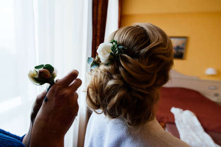 Hairdresser makes hairstyle for the bride. Bride morning. The hairdresser decorates the bride's hair...