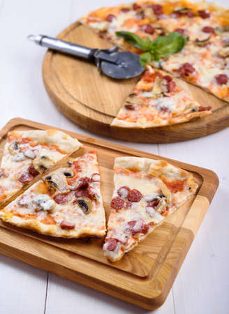 Pizza with mushrooms and hunting sausages on a wooden board.の写真素材