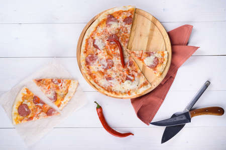 Pizza diablo with salami, pepper and tomato sauce on a wooden boardの写真素材