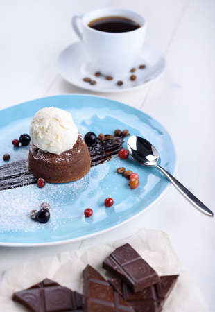 Chocolate fondant with ice cream, pieces of chocolate and coffee on a white tableの写真素材