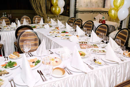 Table setting. Table served for wedding banquet, close up view. White napkin on a white empty plate on a dining tableの写真素材