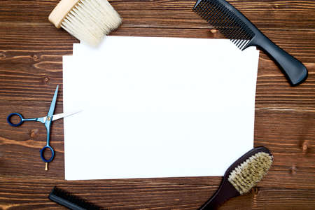 Hairdresser tools on wooden background. Blank card with barber tools flat lay. Top view on wooden table with scissors, comb and brush with empty white paper, free space. Barbershop, manhood conceptの写真素材