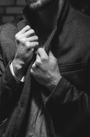 Man holding his jacket collar. Dramatic portrait of a young man pulling his  jacket by collar. Man holding both hands on his tuxedo jacketの写真素材