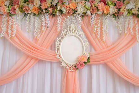 Place for newlyweds decorated with flowers and peach cloth with an empty wedding frame for names of the bride and groom.の写真素材