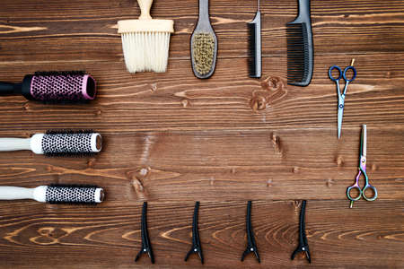 Hairdresser tools on wooden background. Top view on wooden table with scissors, comb, hairbrushes and hairclips, free space. Barbershop, manhood conceptの写真素材