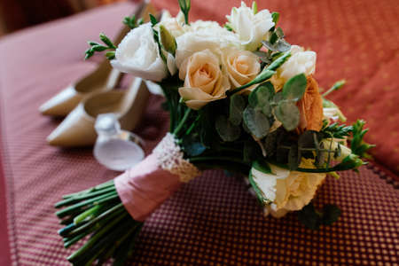 Beautiful lush wedding bouquet near the bride's shoes and perfume in blurの写真素材
