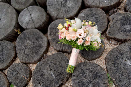 Wedding bouquet of peach roses and white orchids on stumpsの写真素材