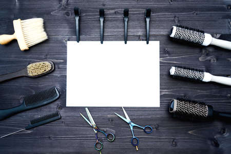Hairdresser tools on wooden background. Blank card with barber tools flat lay. Top view on wooden table with scissors, comb, hairbrushes and hairclips with empty white paper, free space. Barbershop, manhood conceptの写真素材