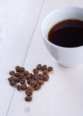Coffee in a white cup on a white background/ Heart made of coffee beans.の写真素材