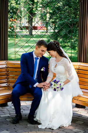 The bride and groom sit on a bench and hold handsの写真素材