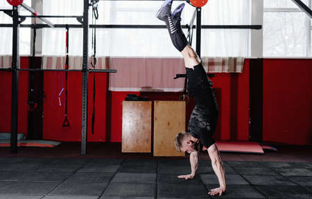 Athlete walking on his hands standing upside down in gym. Crossfit training. Workout lifestyle...