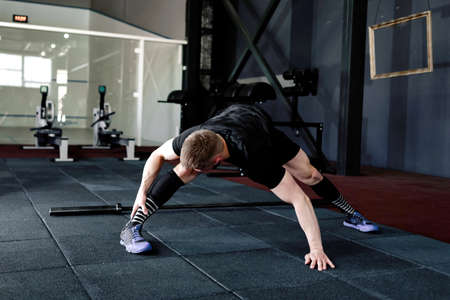 Young man preparing muscles before training. Muscular athlete exercising. Fit man stretching. Professional sportsman warming-upの写真素材