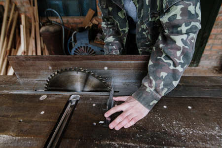 Carpenter measures the width of the board with a calipers  in the workplace. Circular saw. Carpenter toolの写真素材