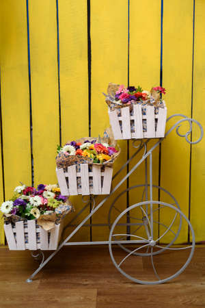 ?olored gerberas in wooden boxes on metal on a yellow background. Flower decorationsの写真素材