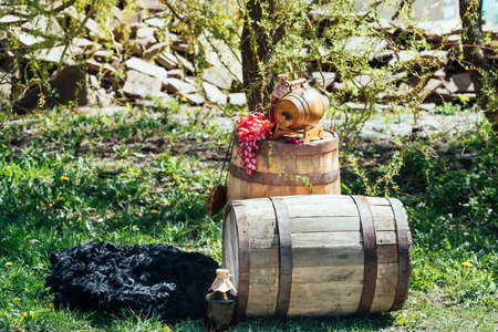 Old wooden wine barrel with bottle of wine and grapes on it. Wedding decorations outdoorsの写真素材