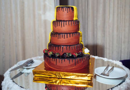 Round multi tiered  yellow and brown wedding cake with strawberries, roses and chocolate icing....