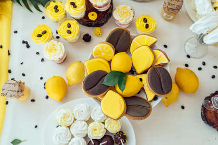 Holiday candy bar in yellow and brown color. Wedding candy bar served with lemon biscuits, cake pops, desserts in glasses, lemons and coffee beansの写真素材
