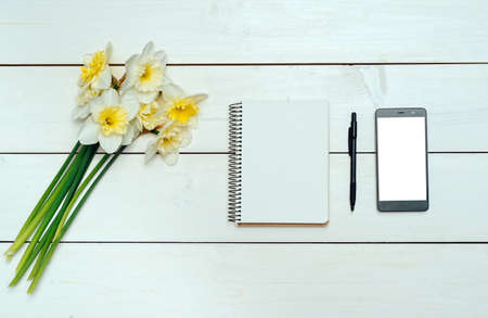 Yellow bouquet of narcissus on white wooden background. Blank card flat lay. Top view on table with...