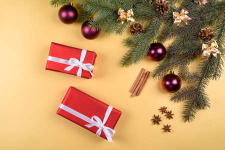 Christmas background with red gift boxes, fir tree branches with glass balls, pine cones, cinnamon...