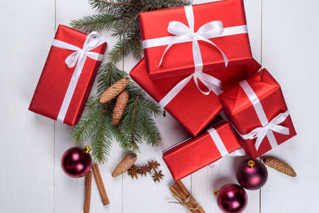 Christmas background with red gift boxes, fir tree branches, pine cones, glass balls, cinnamon...