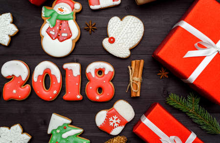 Happy new year 2018 sign symbol with red and white gingerbread cookies on dark wooden background, copy space. Top view, flat lay. Christmas cookies, santa, fir tree, snowflake, cinnamon. free spaceの写真素材