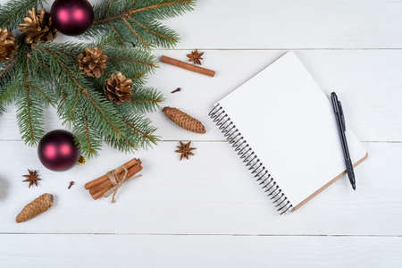 Top view of blank notebook on white wooden background with xmas decorations, copy space. Christmas...
