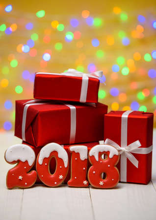 New year 2018 made with gingerbread cookies with bokeh and lens flare pattern on golden background, copy space. New Year 2018 or Christmas background with gingerbread cookies and red gift boxesの写真素材