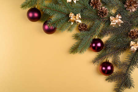 Christmas background with fir tree branches with glass balls, pine cones and bows on golden background, free space. Flat lay, top view with copy spaceの写真素材