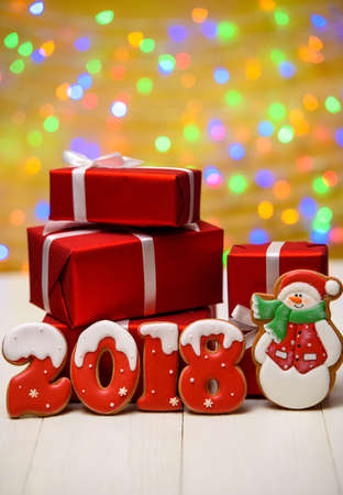 New year 2018 made with gingerbread cookies with bokeh and lens flare pattern on golden background, copy space. New Year 2018 or Christmas postcard with gingerbread cookies and red gift boxesの写真素材