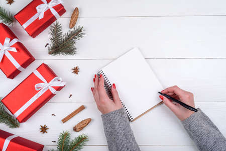 Top view of Christmas background with blank empty diary and girl's hands with pen writing goals on white wooden background, free space. Flat lay, top viewの写真素材