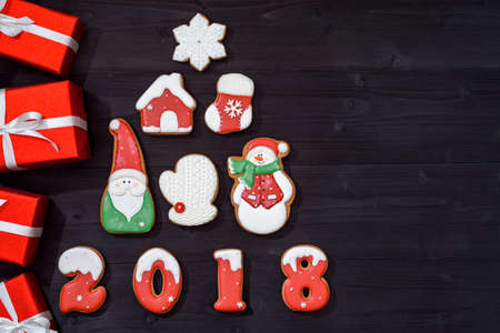 Christmas background with fir tree made from gingerbread cookies and red gifts on wooden background, copy space. New Year 2018 postcard with gingerbread snowman, santa, snowflake, house, mitten, sockの写真素材
