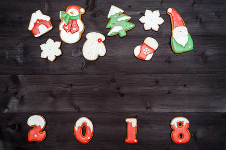 Happy new year 2018 sign symbol from red and white gingerbread cookies on dark wooden background, copy space. Top view, flat lay. Christmas cookies border, free space. Christmas backgroundの写真素材