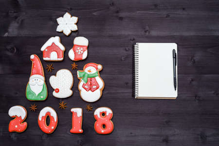 Christmas background with fir tree made from gingerbread cookies and blank notebook with pen on wooden background, copy space. New Year 2018 postcardの写真素材