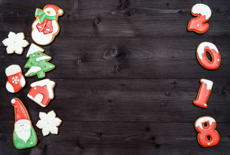 Happy new year 2018 sign symbol from red and white gingerbread cookies on dark wooden background, copy space. Top view, flat lay. Christmas cookies border, free spaceの写真素材