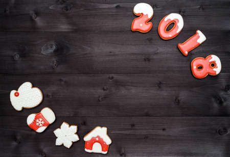 Happy new year 2018 sign symbol from red and white gingerbread cookies on dark wooden background, copy space. Top view, flat lay. Christmas cookies, free spaceの写真素材