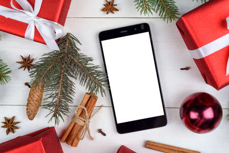 Close up of mobile smart phone with blank white screen for app presentation with Christmas decorations on wooden background, copy space. Flat lay, top view. Christmas application mock up templateの写真素材