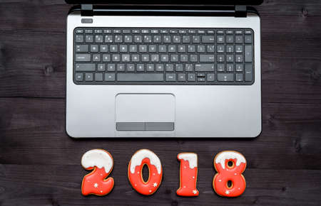 Top view of office table desk with open laptop and new year 2018 sign symbol from gingerbread cookies. Business holidays concept. Workspace with laptop and christmas decorations on wooden backgroundの写真素材