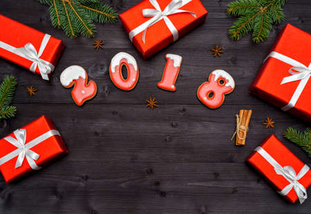 Happy new year 2018 sign symbol from red and white gingerbread cookies on dark wooden background with red gift boxes, copy space. Top view, flat lay. New Year or Christmas postcardの写真素材
