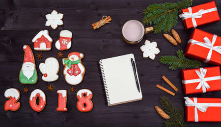 Top view of blank notebook on wooden background with xmas decorations, copy space. Christmas background with empty notebook, gingerbread cookies and hot cocoa, red gift boxes. Flat layの写真素材