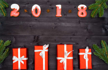 Happy new year 2018 sign symbol from red and white gingerbread cookies on dark wooden background...