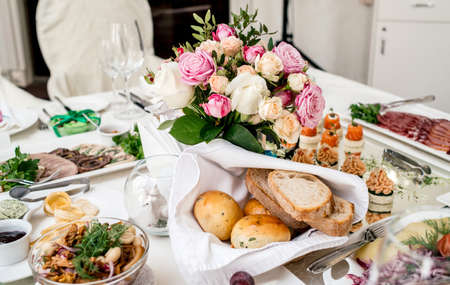 Beautiful wedding bouquet of cream and pink roses in glass vase on dinner table, selective focus. Table setting at a luxury wedding reception. Flowers on the tableの写真素材
