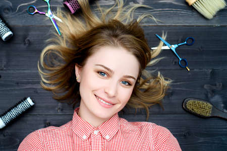 Happy smiling young woman in plaid shirt with hairdresser tools among her. Top viewの写真素材
