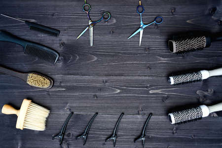 Hairdresser tools on wooden background. Top view on wooden table with scissors, comb, hairbrushes and hairclips, free spaceの写真素材