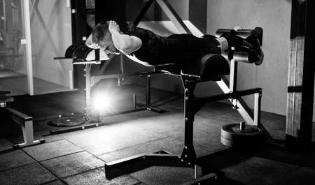 Young man training back muscles. Muscular athlete exercising. Full body length portraitの写真素材