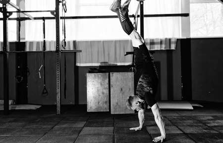 Athlete walking on his hands standing upside down in gym. Crossfit training. Workout lifestyle concept.  Full body length portraitの写真素材