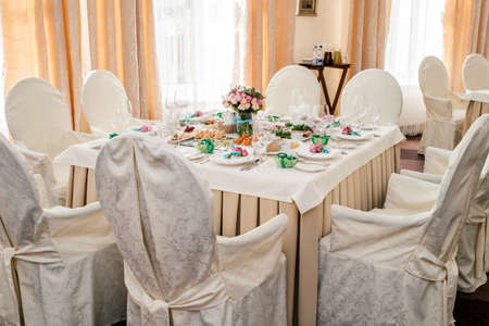 Chairs with white cloth and table for guests served for wedding banquet with flowers. Dinner table for wedding banquetの写真素材