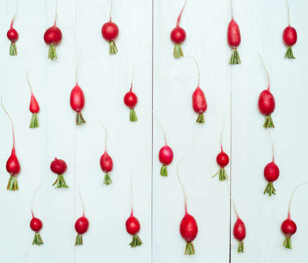 Fresh organic red radishes with tops on white wooden background. Top view. Vegetable backgroundの写真素材