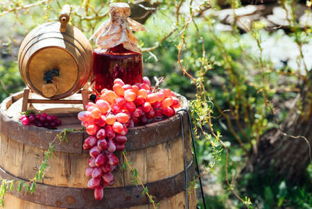 Old wooden wine barrel with bottle of wine and grapes on it. Wedding decorations outdoorsの写真素材