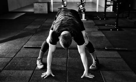 Young man preparing muscles before training. Muscular athlete exercising crossfit. Fit man stretching. Professional sportsman warming-up. Workout lifestyle concept. の写真素材